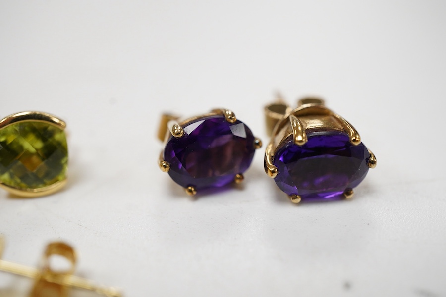 A pair of chequerboard cut peridot set 18ct stud earrings, a pair of amethyst set 9ct stud earrings and three costume pairs of earrings.